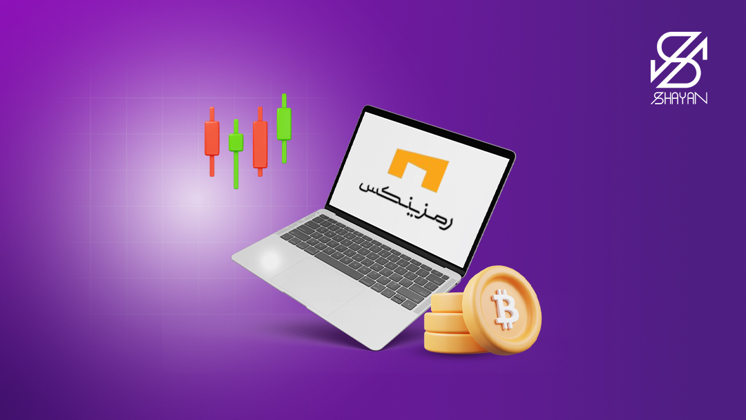 تصویر طراحی شده لوگوی صرافی رمزینکس روی صفحه لپتاپ به همراه سکه‌های بیت کوین در کنار آن 