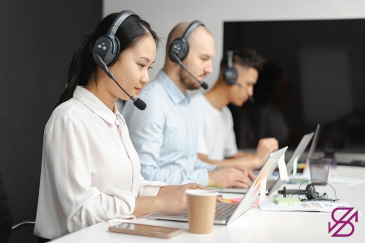 تصویر افرادی اب هدفون‌های روی گوش و نشسته در کنار هم مشغول کار با لپتاپ که گویی بخش نیروهای بخش پشتیبانی گلدیکا هستند 